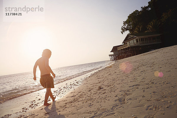 Silhouettierter Junge spaziert am sonnenbeschienenen Strand  Insel Rawa Malaysia