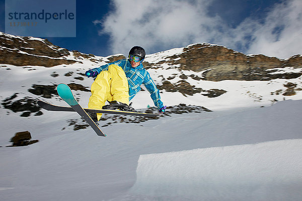 Männlicher Skifahrer in der Luft mit gekreuzten Skiern