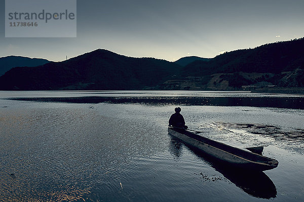 Silhouette einer Bergkette mit Mann im Boot  Lugasee  Yunnan  China