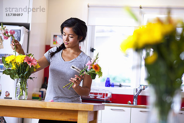 Junge Frau arrangiert Blumen in der Küche