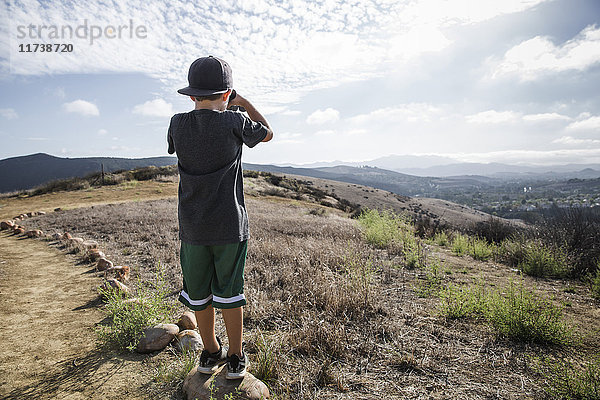 Rückansicht eines Jungen  der durch ein Fernglas vom Stein des Fußweges aus sieht  Thousand Oaks  Kalifornien USA