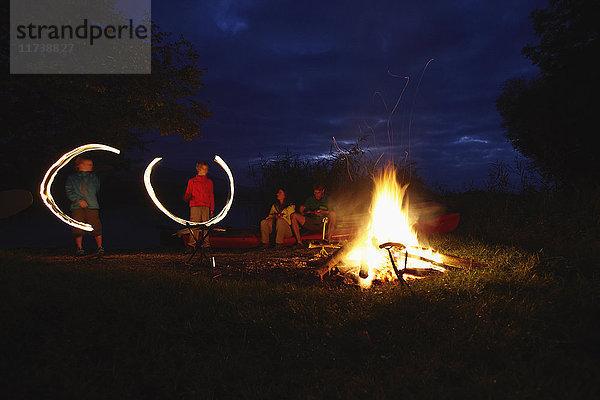 Familie am Lagerfeuer  Kinder machen Lichtspuren in der Luft