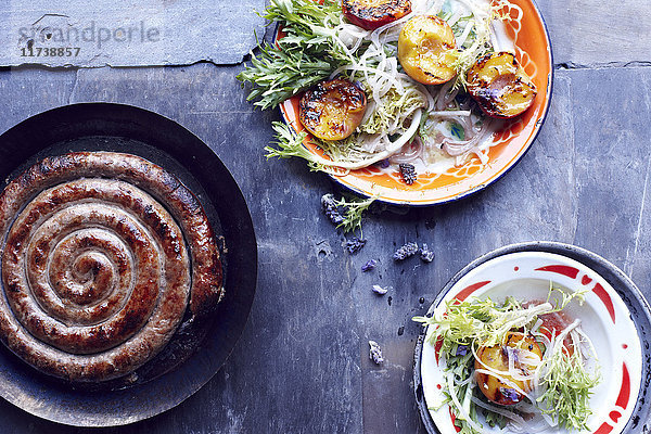 Toulouser Bratwurst in der Pfanne mit Pfirsichsalattellern