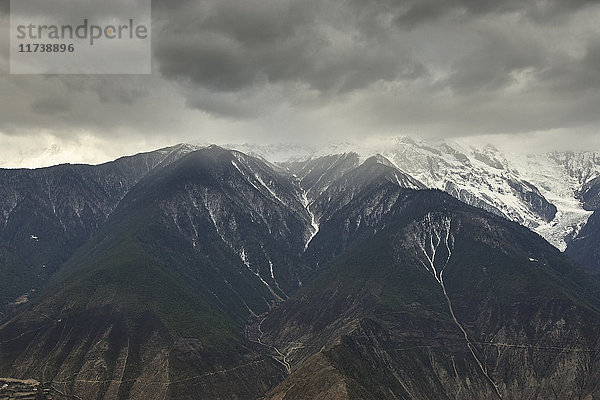 Dramatisch bewölkter Himmel und schneebedeckte Bergkette  Bezirk Shangri-la  Yunnan  China