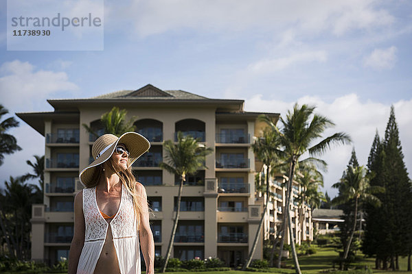 Mittlere erwachsene Frau mit Sonnenhut und Bikini beim Spaziergang vor dem Hotel  Maui  Hawaii  USA