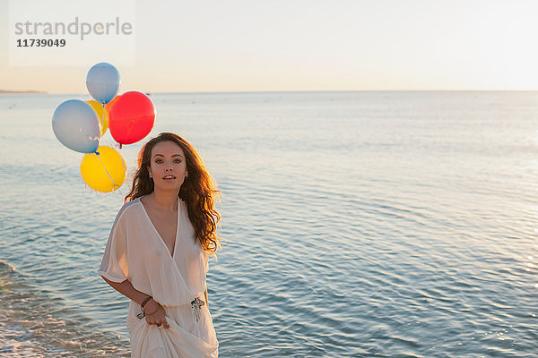 Porträt einer jungen Frau am Strand mit Luftballons  Castiadas  Sardinien  Italien