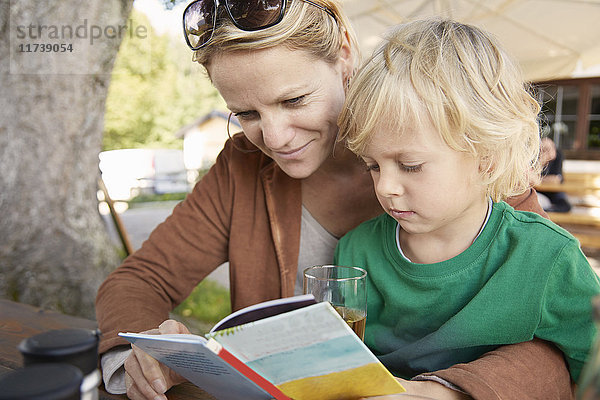Mutter und Sohn lesen gemeinsam im Freien ein Buch