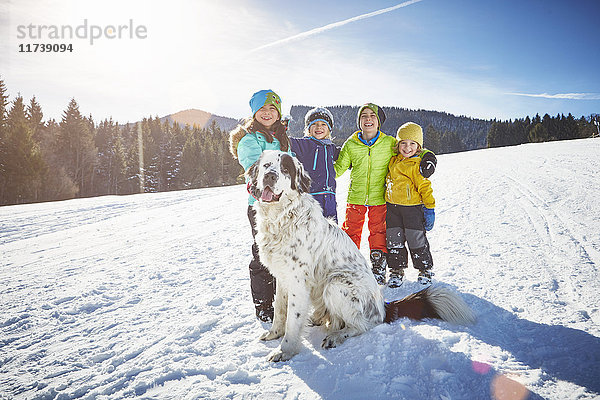 Kinder und Haushund spielen gerne im Schnee
