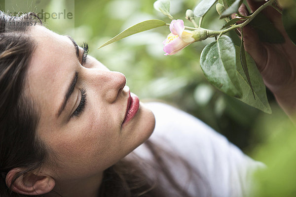 Nahaufnahme eines Porträts einer jungen Frau  die eine Blüte hält