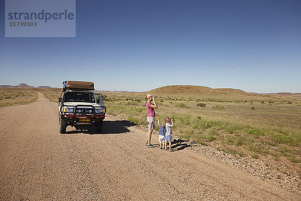 Geländewagen geparkt  während Mutter und Kinder die Aussicht genießen  Sesfontein  Kaokoland  Namibia