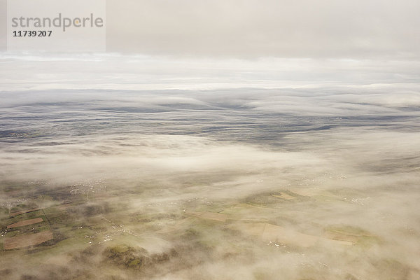 Land durch dünne Wolkenschicht gesehen