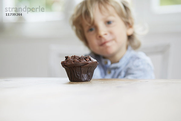 Junge starrt auf Schokoladenmuffin