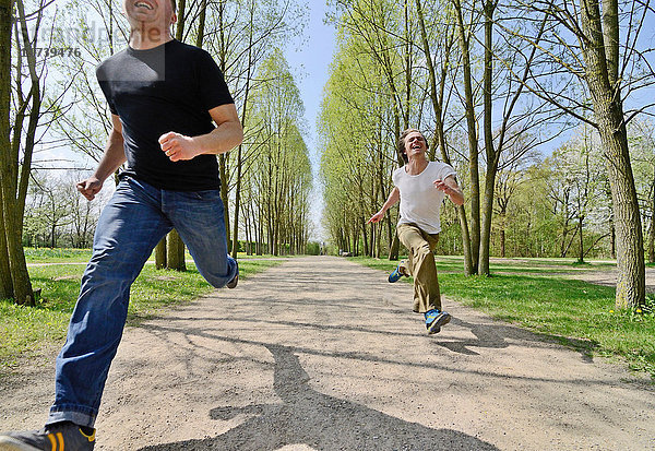 Mittelgroße erwachsene Männer  die auf dem Parkweg um die Wette laufen