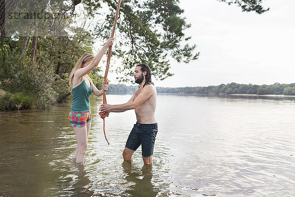 Junges Paar schwingt Seil über dem See