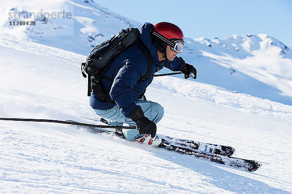 Männlicher Skifahrer rast den Berg hinunter