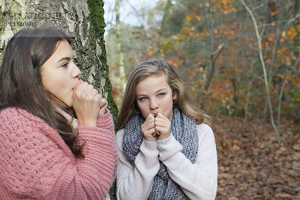 Teenager-Mädchen im Wald halten den Mund  ahmen Tiergeräusche nach und schauen weg