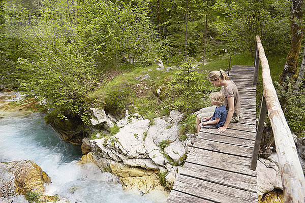 Reife Frau mit Sohn auf Holzsteg sitzend  Bovec  Soca  Slowenien