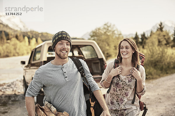 Junges Paar bereitet sich zum Wandern vor  trägt Brennholz  lächelt