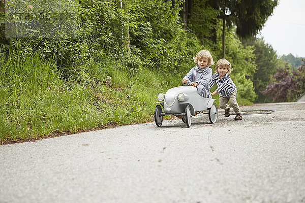 Zwei Jungen spielen mit einem Oldtimer-Spielzeugauto