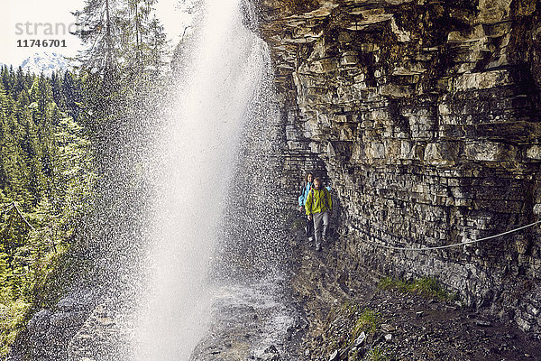 Junges Paar geht unter einem Wasserfall hindurch  Tirol  Österreich