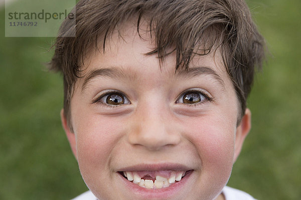 Porträt eines Jungen  der lächelt und eine Lücke von einem verlorenen Zahn zeigt