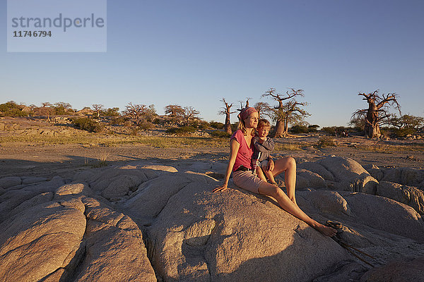 Mutter und Sohn auf einem Felsen sitzend  die Aussicht betrachtend  Gweta  makgadikgadi  Botswana