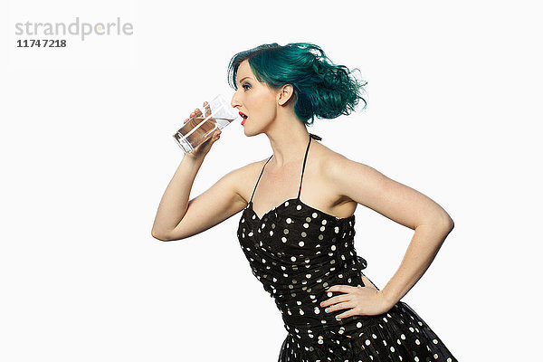 Junge Frau mit grünen Haaren trinkt Wasser vor weissem Hintergrund