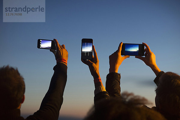 Freunde fotografieren mit Smartphone in der Dämmerung