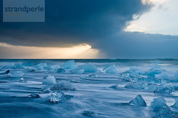 Eisberge am Strand bei stürmischem Himmel  Jokulsarlon  Island