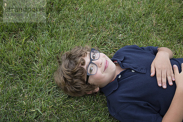 Porträt eines Jungen  der auf dem Rücken auf Gras liegt