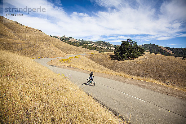 Erhöhter Blick eines jungen Mannes beim Mountainbiken auf einer Landstraße  Mount Diablo  Bay Area  Kalifornien  USA