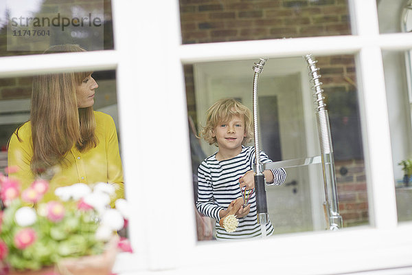 Mutter und Sohn beim Abwasch  Blick durchs Fenster