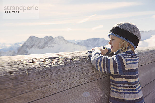 Junge schaut über eine Holzbarriere auf den Berg