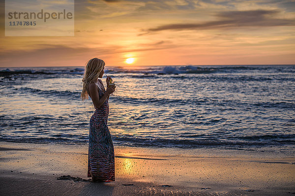 Junge Frau trinkt Cocktail am Strand bei Sonnenuntergang  Tamarindo  Costa Rica