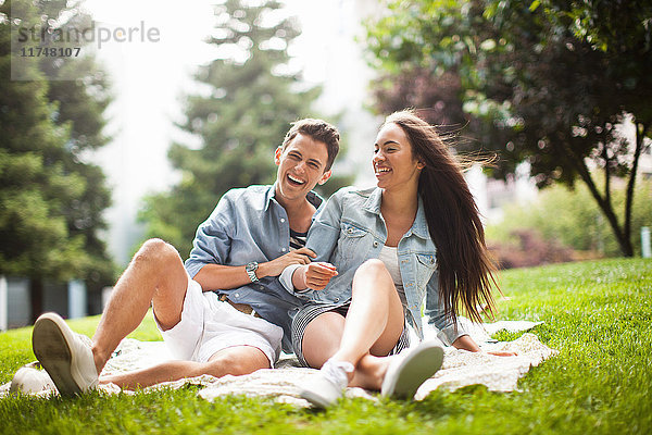 Junges Paar sitzt im Park und lacht