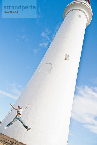 Junger Mann springt am Split-Point-Leuchtturm  Melbourne  Australien