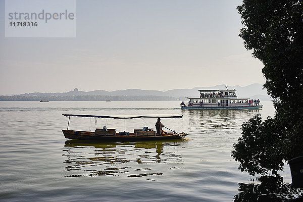 Silhouettenansicht eines Fischerbootes und eines Flussbootes auf dem Westlake  Hangzhou  China