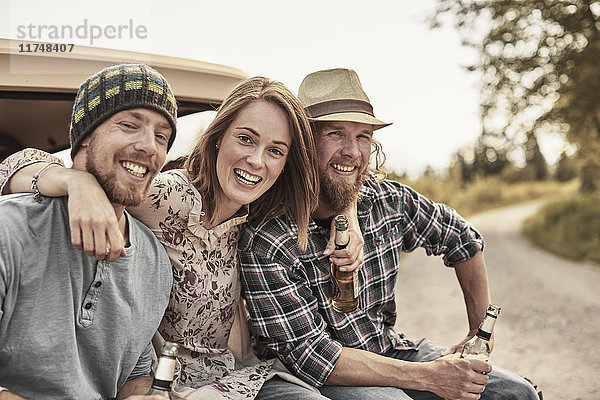 Drei Personen  die Bierflaschen halten  in die Kamera schauen und lächeln