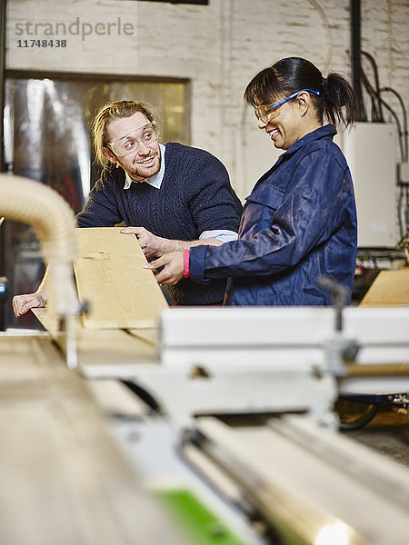 Mann und Frau bereiten in der Druckwerkstatt Holzplanken vor