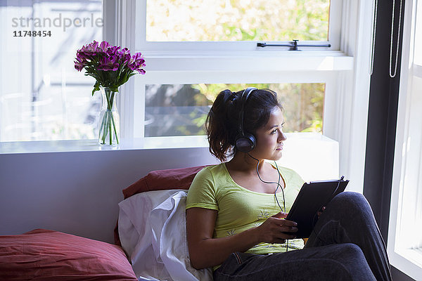 Junge Frau benutzt digitales Tablett am Bett