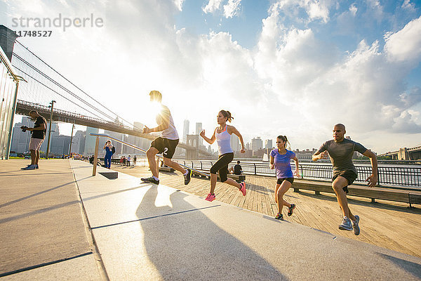Vier rennende Freunde rennen die Treppe am Fluss hinauf  New York  USA