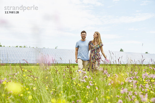 Junges Paar beim Spaziergang durch das Feld neben dem Solarpark