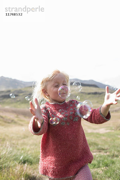 Junges Mädchen mit geschlossenen Augen läuft  um Blasen zu fangen