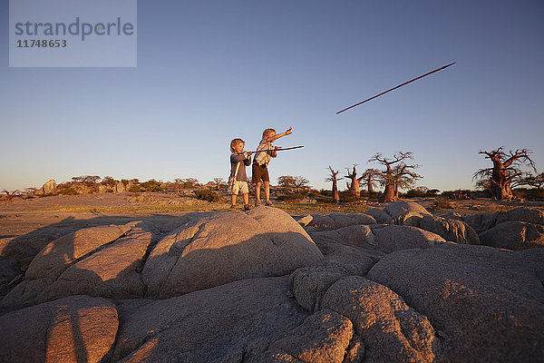 Zwei kleine Jungen stehen auf einem Felsen und werfen Speere  Gweta  makgadikgadi  Botswana