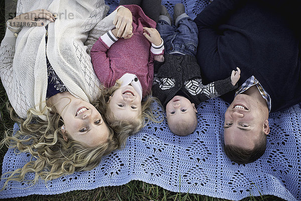 Portrait eines Paares mittlerer Erwachsener auf einer Picknickdecke mit Tochter und Junge