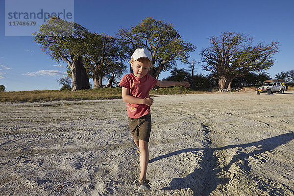 Junge spielt auf Schotterstraße  Nxai-Pan-Nationalpark  Kalahari-Wüste  Afrika