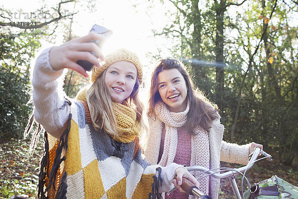 Teenager-Mädchen im Wald benutzen Smartphone  um sich selbst zum Lächeln zu bringen