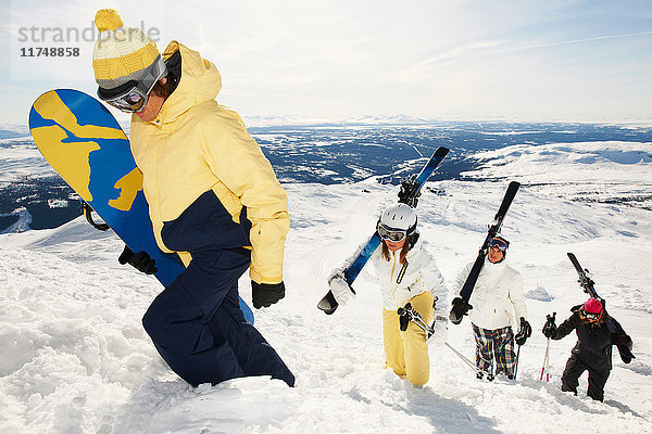 Snowboarder und Skifahrer  die Ausrüstung auf den Berggipfel tragen