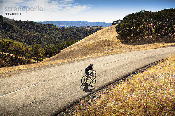 Erhöhte Ansicht eines jungen Mannes beim Mountainbiken auf einer Landstraße  Mount Diablo  Bay Area  Kalifornien  USA