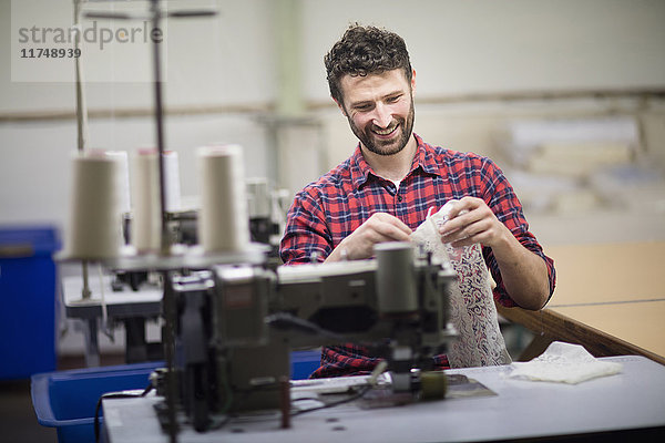 Männlicher Textildesigner benutzt Nähmaschine in alter Textilfabrik